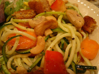 Zucchini noodles with vegetables and peanut sauce on white plate with cashews