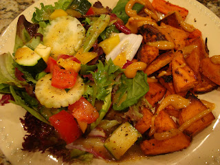 Tossed salad of greens and vegetables on plate with roasted sweet potatoes and carrots