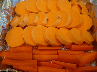 Sliced up sweet potato and carrot sticks in tinfoil lined pan