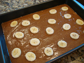 Finished cake batter poured into cake pan and topped with sliced bananas