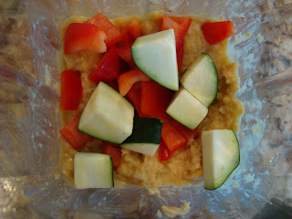 Blended hummus ingredients in blender with sliced peppers and zucchini added