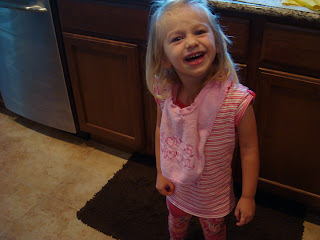 Little girl wearing pink smiling standing in kitchen