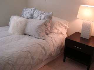 Bed with lots of pillows and table with lamp on