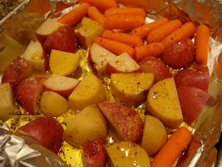 red and yukon gold potatoes, baby carrots with oil, salt, pepper and ginger in foil lined pan
