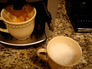 Mug with steamed almond milk and mug in machine brewing espresso