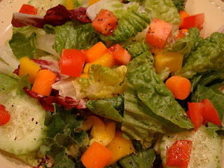 Mixed green salad with diced vegetables in homemade dressing on white plate
