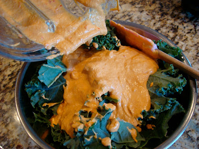 Blended ingredients being poured over bowl of kale