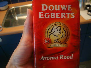 Hand holding Package of Douwe Egberts Aroma Rood