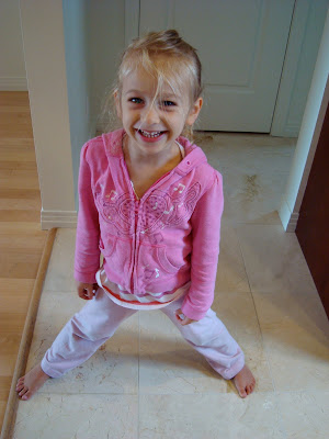 Young girl standing with legs spread smiling by door