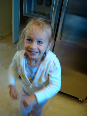 Young girl standing by refrigerator smiling