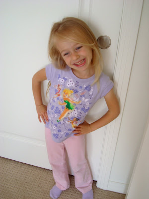 Young girl smiling by door with hands on hips