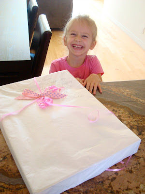 Young girl smiling in front of gift on countertop