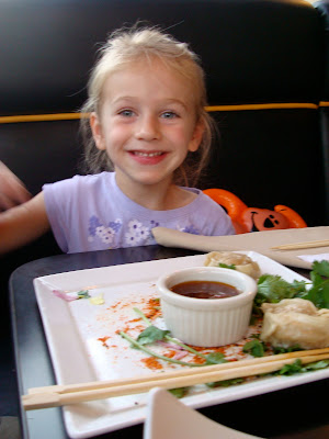 Young girl sitting in booth eating Steamed Potstickers