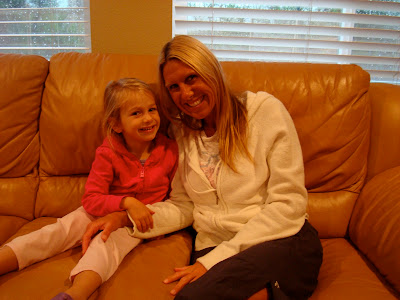 Woman and chid sitting on brown leather couch smiling