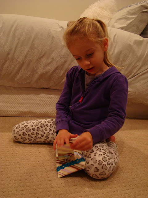 Young girl sitting on floor opening up a gift
