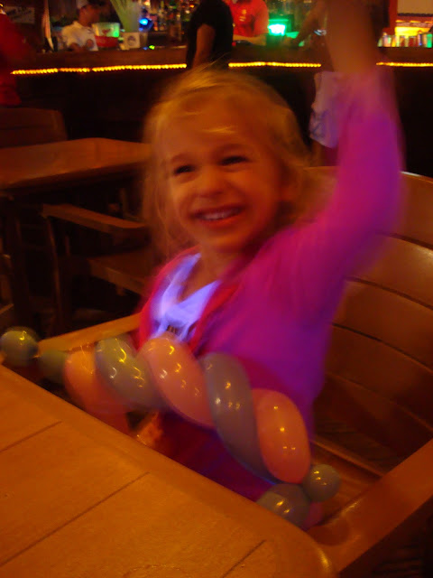 Young girl sitting holding her balloon figure with hand up in air