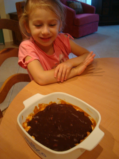 Little girl at table smiling at finished GF Peanut Butter Marshmallow Bars with Vegan Chocolate Frosting