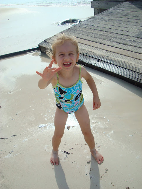 Young girl next to pier with arm up in bathing suit