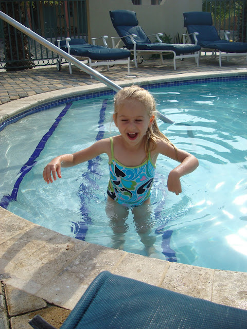 Young girl standing on steps in swimming pool