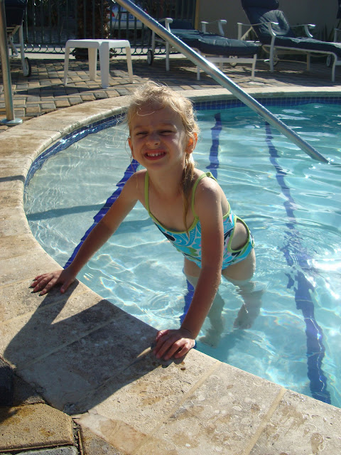 Young girl on pool steps leaning over edge of pool