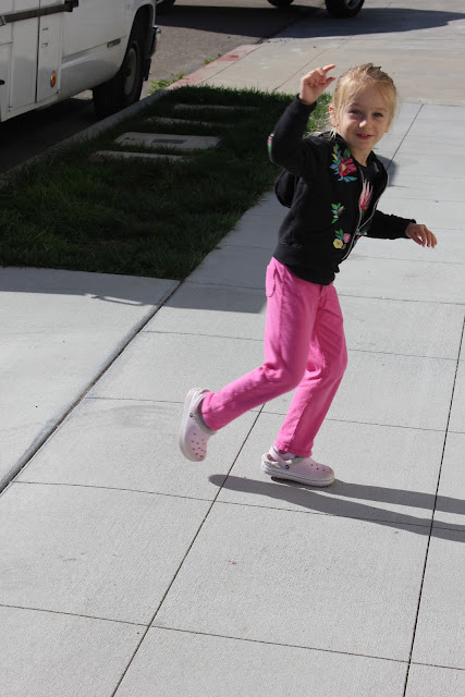 Young girl running trying to wave on sidewalk