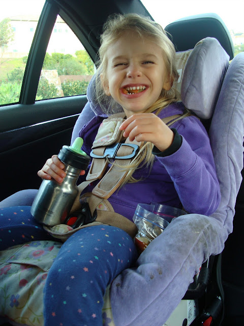 Young girl in carseat eating snacks