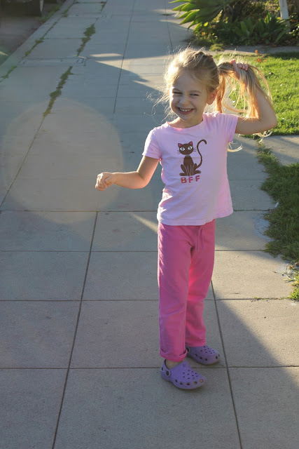 Young girl walking down sidewalk holding ponytail