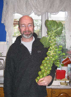 Andy holding a stalk of Brussels sprouts in the kitchen
