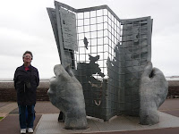Me next to sculpture of giant hands holding a map