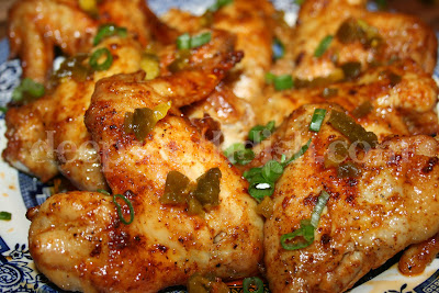 Oven baked hot wings made with a buttery Louisiana hot sauce and garnished with sliced green onion and chopped jalapenos.