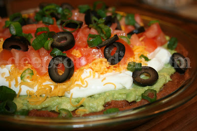 A retro throw-back to the 70s and still popular today, 7 layer dip is made with refried beans, avocado or guacamole spread, sour cream, shredded cheese, tomatoes, black olives and green onion, and is still a party favorite.