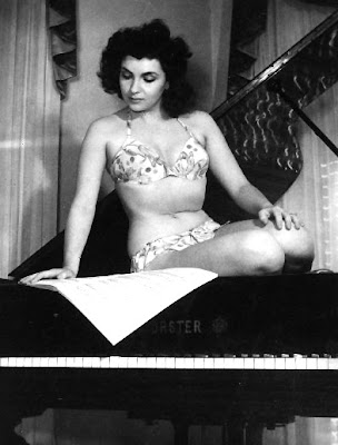 Gina Lollabrigida is reading music and not a book, but where else are you gonna find a picture of a scantily clad Gina sitting in a piano?