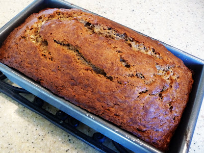 A baked loaf of orange banana bread in a loaf pan. 