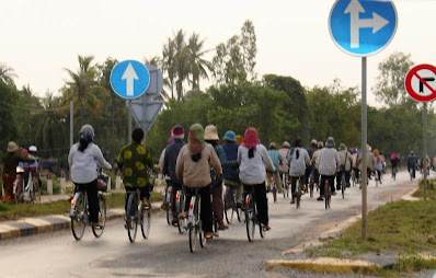 Cambodgiens à vélo sur une route de campagne, Cambodge