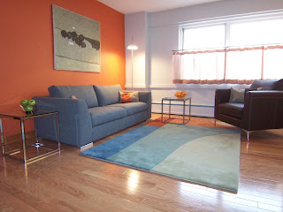 contemporary living room with orange accent wall grey walls and charcoal grey sofa Design Within Reach Albert Armchair DWR