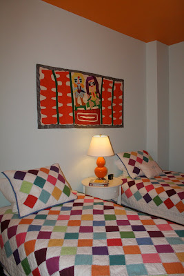 light blue bedroom, orange ceiling, colorful wall hanging
