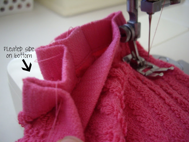 A sewing machine sewing a pleat onto a dishtowel. 