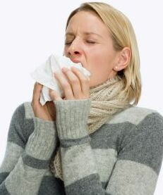 woman sneezing into a tissue