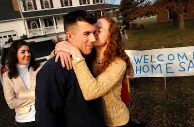 With his sister Molly (left) looking on, 1st. Lt. Sam Chamberlain receives a kiss from his wife, Gretchen, during a visit to his parents' home in Stafford County. Chamberlain recently completed a tour of duty in Iraq. Photo by FLS Bob Martin
