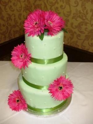 Four tier green round wedding cake with bright pink flowers