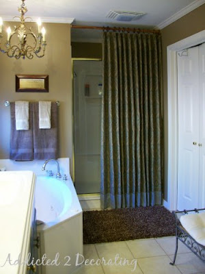 Master bathroom makeover--brass frame on shower surround minimized with custom shower curtain, chandelier above bathtub.