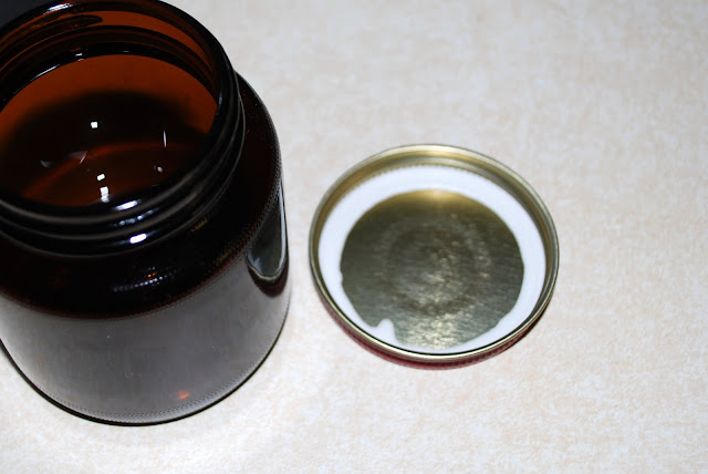 A small, empty jar that held yeast, and its lid. The lid has a white rubber strip around the edge.