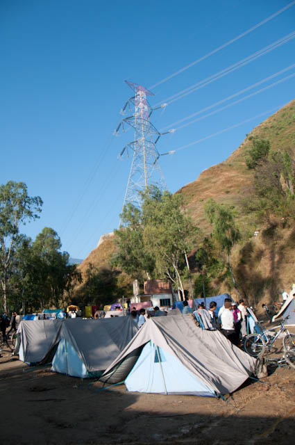 MTB Riders getting ready for second day Hiking and Biking : Posted by VJ SHARMA on www.travellingcamera.com : Hope you have already check other posts on MTB Himachal 2010 which talks about flag-off from Ridge ground, Rides during first day and some glimpses of this event... Today I am going to share some of the photographs of first morning(after camping) of this event... So here are few photographs of second day morning with some details about the activities around the camp side...Although there was sunlight but it was too cold in the morning... Many of us were hesitating to have bath there but finally we got motivated after seeing hot water on other corner of the camping ground... I think you can make a guess that why people are standing behind these tents and nobody in the front... Coz everyone is looking for sunlight and no one can't afford to stand in shadows :-)Mr. Dutta from Maharashtra assisting other rider in repairing the bike... Dutta ji, a passionate biker from Maharashtra who were bare feet throughout the journey... And you can also see that he is half T-Shirt... He is not worried about winters as he always lives like that irrespective of the season... A very humble and calm guy... Nice to meet you Dutta Ji !!!There were few folks who were leaving on second day... This includes some of the riders and few photographers... So everyone was saying bye to each other by getting appropriate details to be in touch... Here Runjhun (PHOTOQUEST participant) meeting Peter to say 'Good-Bye' and 'All the Best !'Due to rough and muddy roads, all the riders needed to take proper care of their bikes.... everyone used to clean and repair their cycles everyday... I was amazed to see people repairing their bikes with ease... They used to disassemble their bikes and re-assemble again after cleaning and repairing... Many times they used to talk about various types of bikes, companies, gears and other accessories... although I was not able to relate to most of the stuff... The only thing I noticed was that Military people and Nepali gang had best bikes in the camp...Folks are ready and just waiting for the final call from Marshals... Some of the riders are just warming up for the rides... On second day they had to ride till one point (?? KM) and then they had to cross a river to hike a mountain with their bikes.. This whole stretch of hiking was 12 Kilometers... It was very tiring... We were four  PHOTOQUEST participants who were together during this hiking session and all of us were down during the half way... Everyone was hungry and we were not carrying anything with us... On the way we asked for water at a local village an they gave us apples as well :-) ... Those Apples were amazing and now we had some energy to continue...  For rest of the story, I will share another post with Hike and Bike Photographs...Here is a photograph of Shainj School where we stayed during first night of MTB Himachal 2010... Lovely place under blue sky and surrounded by hills... Nothing like it !!!Here comes all the riders ready for various challenges of the day... The man in the front was a retired policeman and was there in MTB for first two days... When I asked 