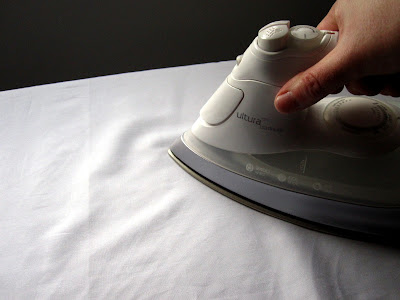 Ironing a piece of white fabric.