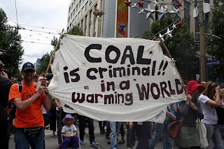 protesters with a banner that says Coal is Criminal in a Warming World