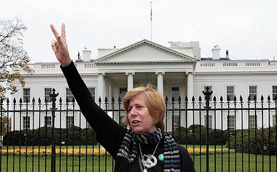 Cindy Sheehan in front of the White House making a peace sign