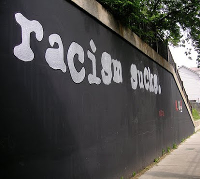 racism sucks painted on a wall