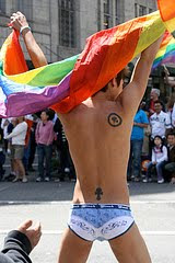 young Asian man in briefs waving rainbow flag at pride parade