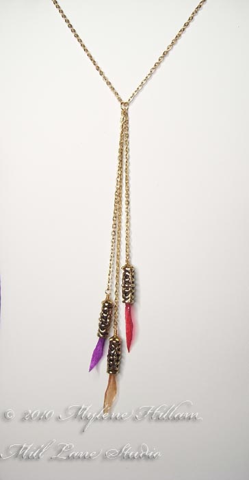 Gold necklace with three dangling tubes filled with purple, red and orange crepe paper that has been coated with resin.