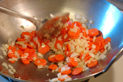 The onions and carrots go in first because they'll require more time to cook than some of the other ingredients.